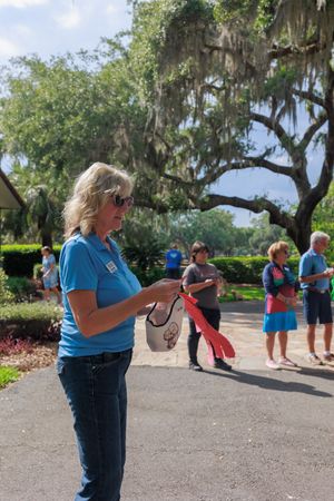 Event volunteers in blue shirts assist with outdoor activities under Spanish moss draped oak trees.