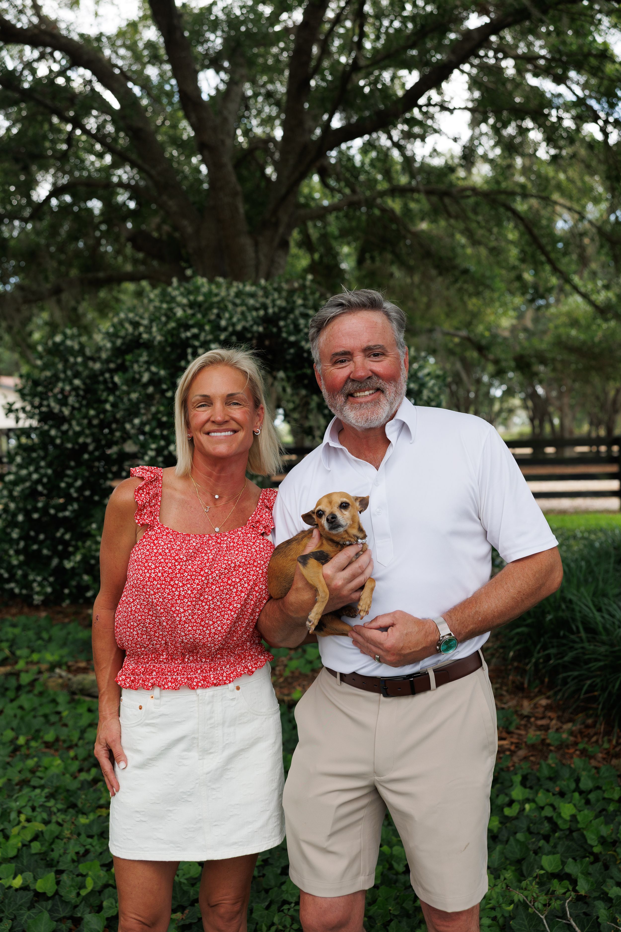 Small brown dog being held at outdoor adoption event.