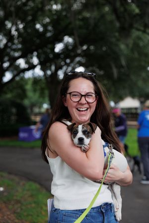 Small dog being cuddled at outdoor adoption event.