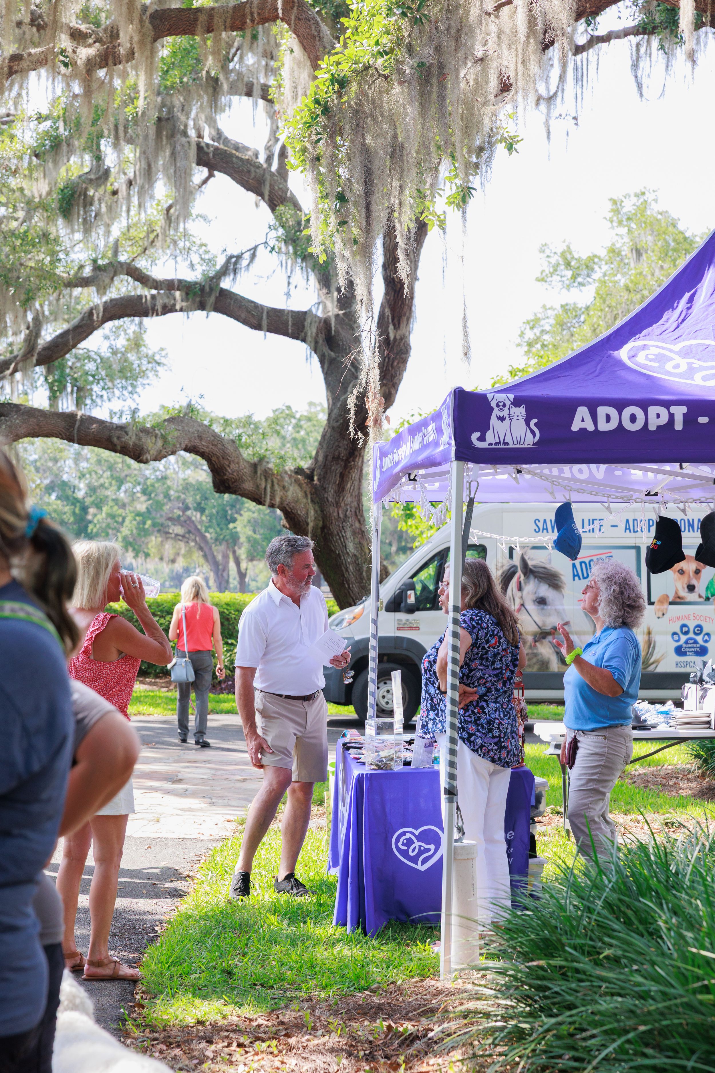 Purple adoption tent set up under moss-covered trees at outdoor event.