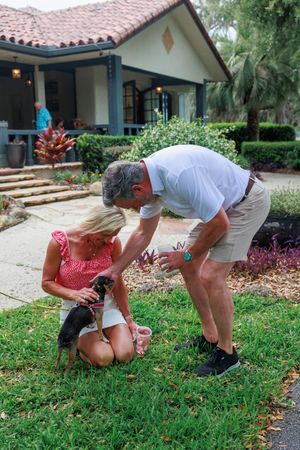 A sequence of photos showing someone bending down to pick up something from a grassy lawn in front of a house.