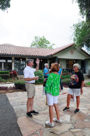 Group mingling on stone patio outside Spanish architecture building.