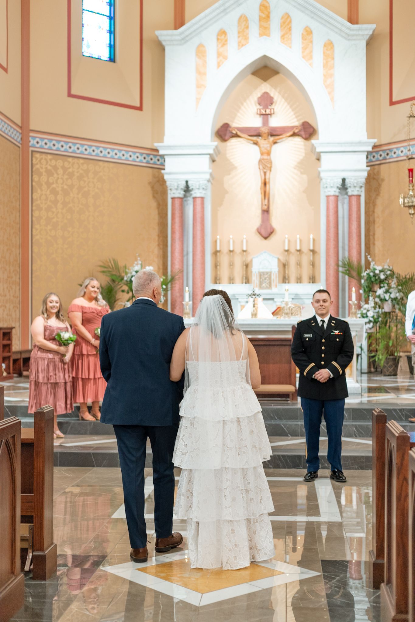 Wedding ceremony in a beautiful Catholic church with pink accents and traditional religious decor.