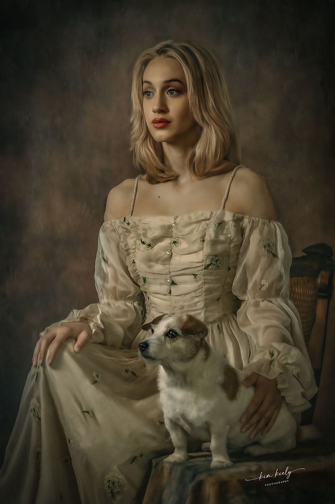 Blonde woman in vintage cream off-shoulder gown seated with a Jack Russell terrier in a classical portrait style.