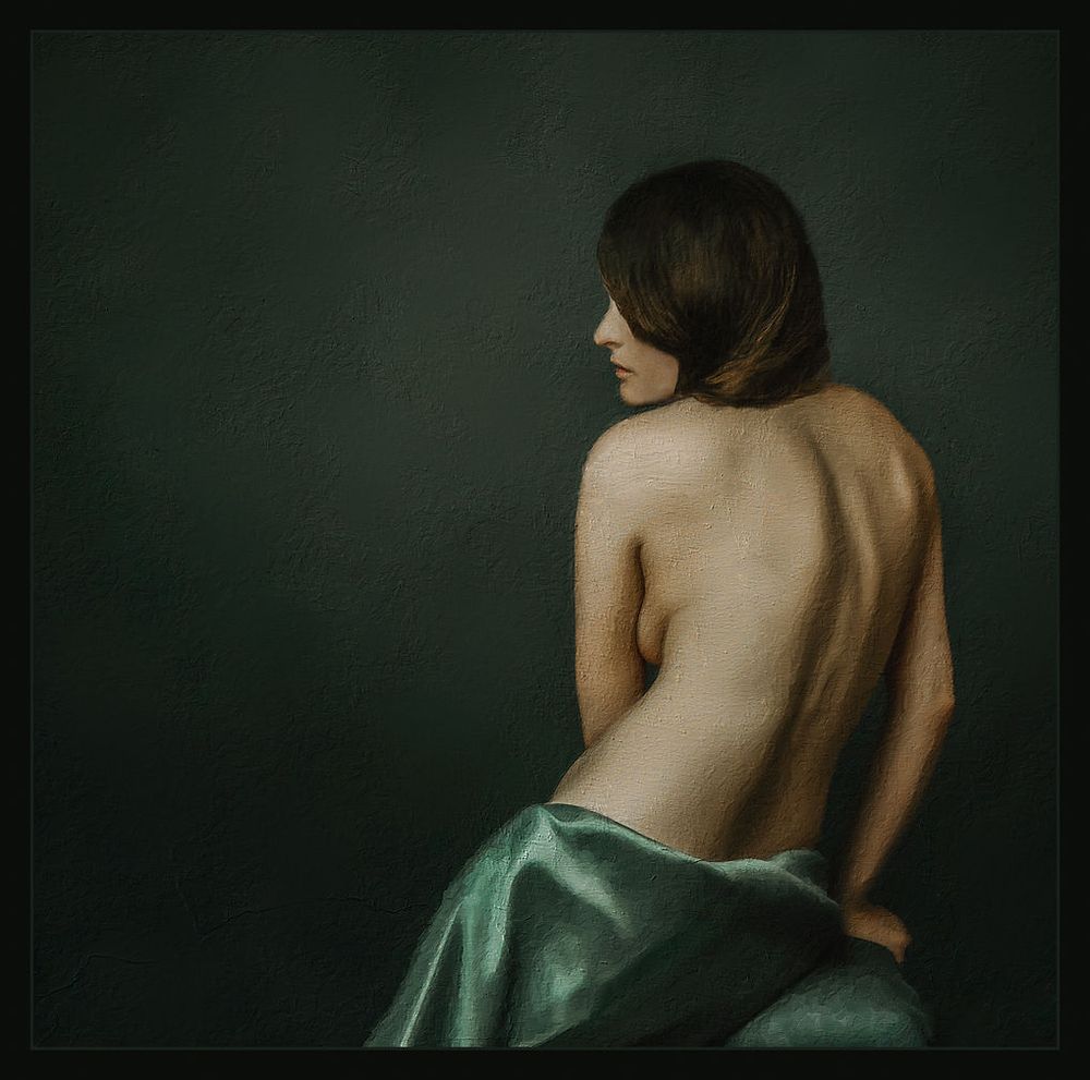 Artistic fine art nude portrait of a woman seen from behind draped in green satin fabric.