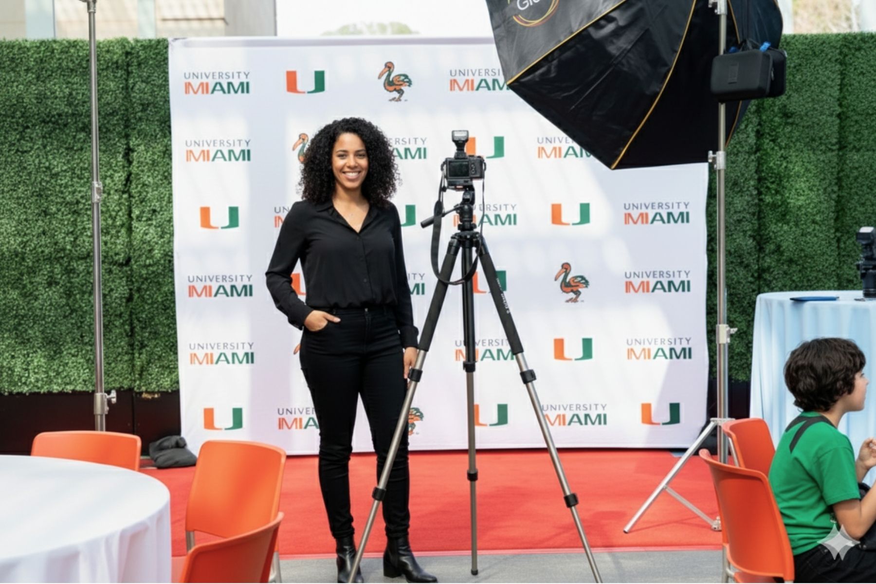 Event photographer capturing photos on a red carpet with backdrop banners at a formal gathering.