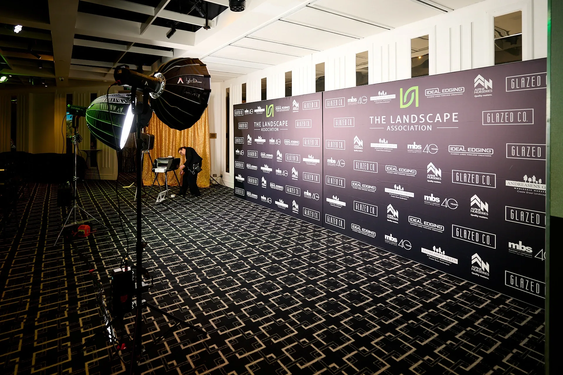 Dimly lit theater or screening room with rows of empty seats and black walls displaying illuminated sponsor logos.