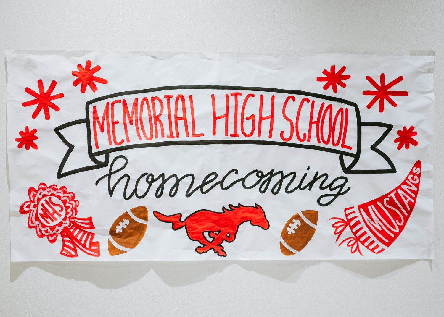 A white banner decorated with red designs shows 'Memorial High School Homecoming' with footballs and mascot illustrations.