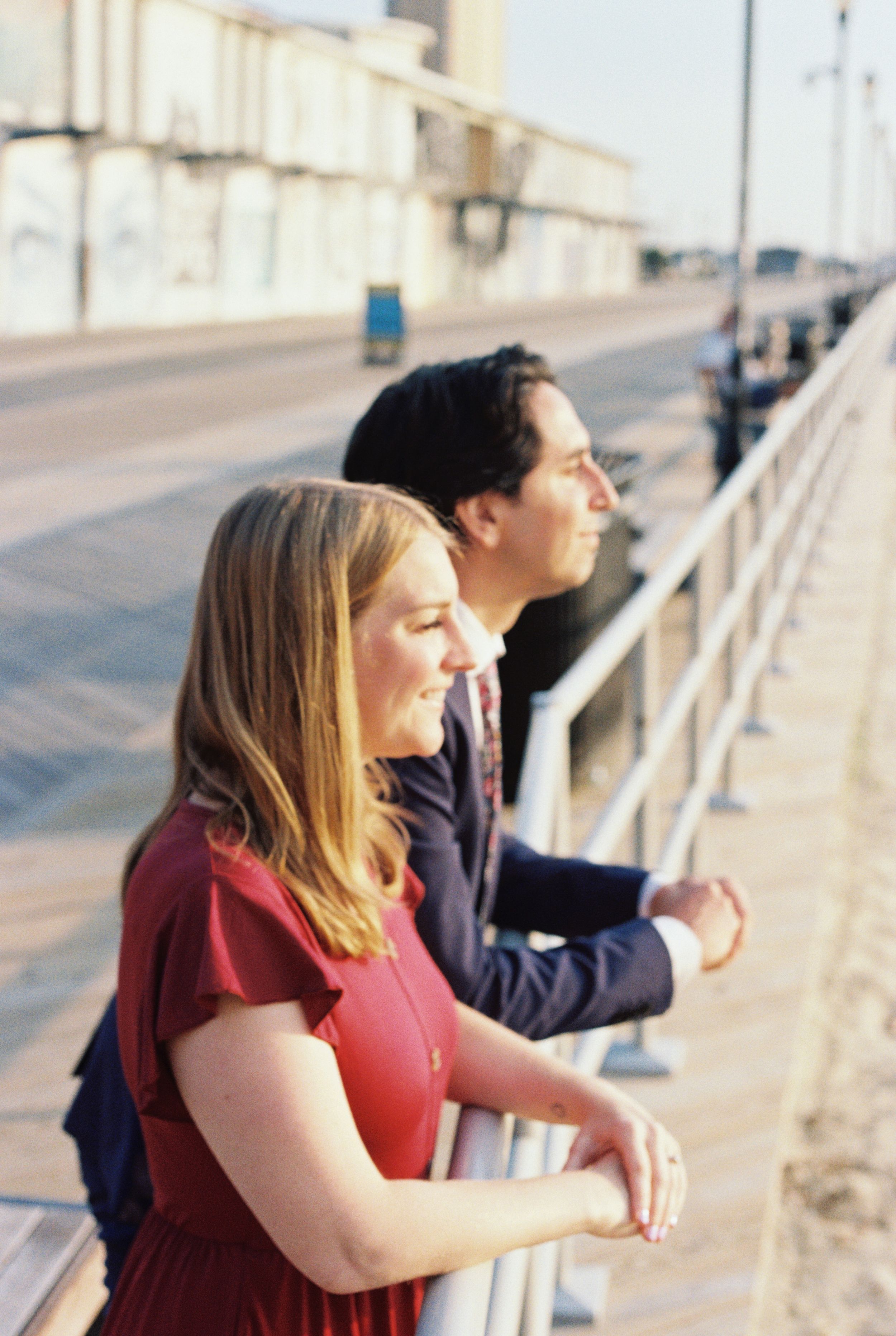 A group stands along a railing looking out at a scenic view during golden hour.