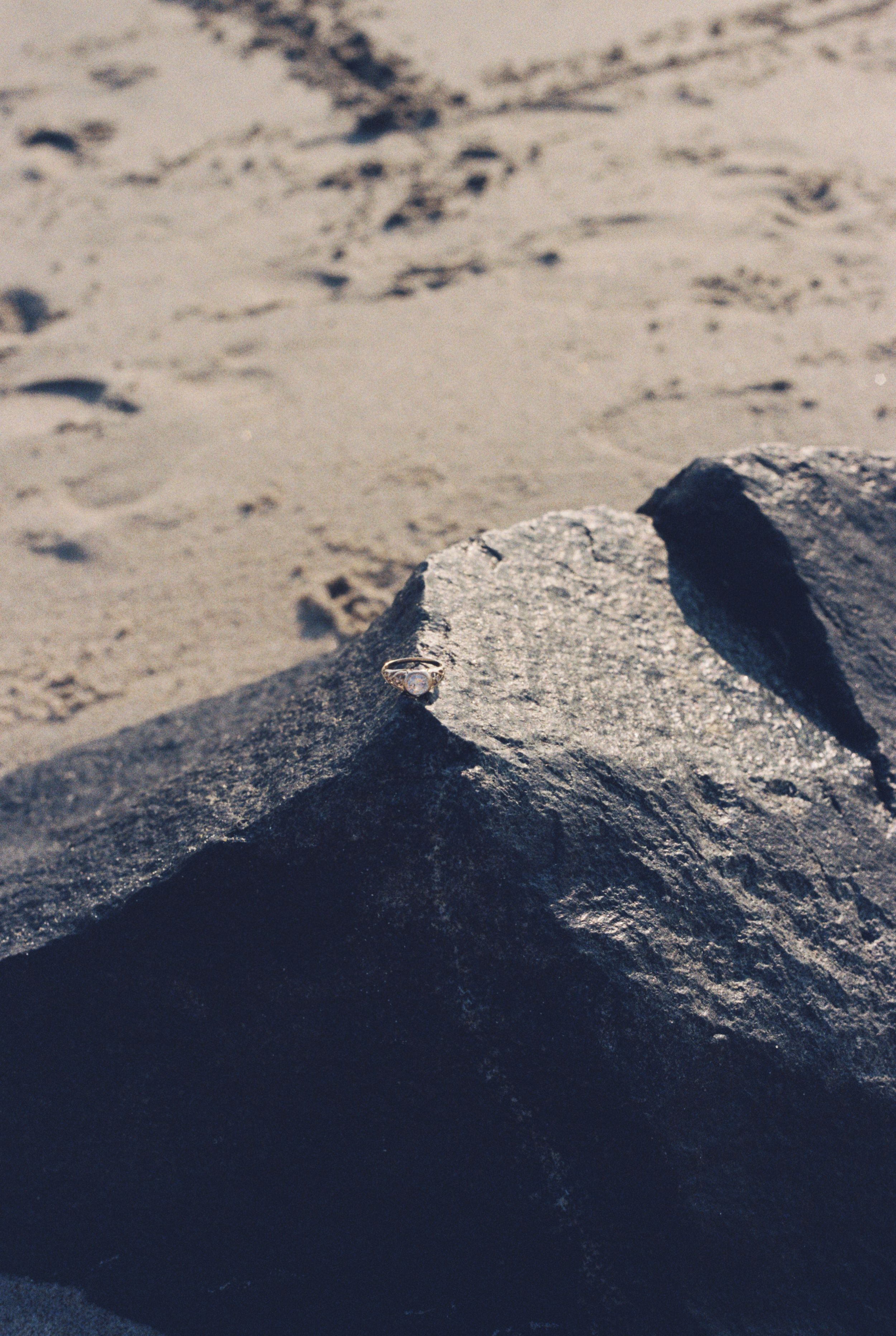 Close-up of dark rocky terrain with shadows and sand in natural lighting.