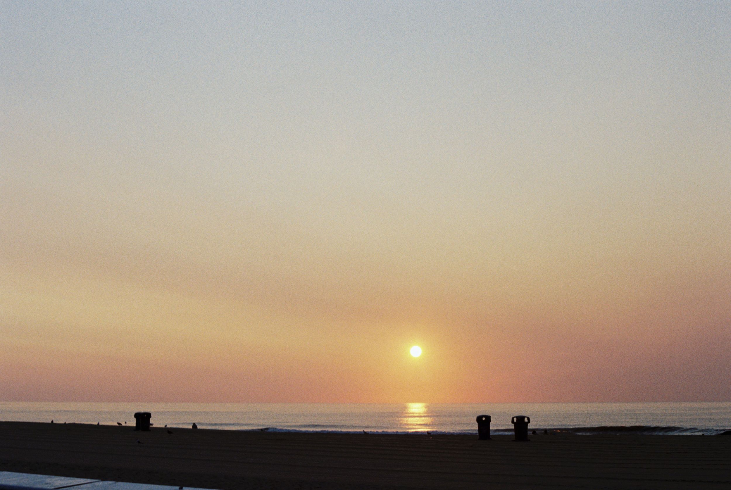 A series of coastal sunset photos showing the sun's progression as it descends into the ocean horizon.