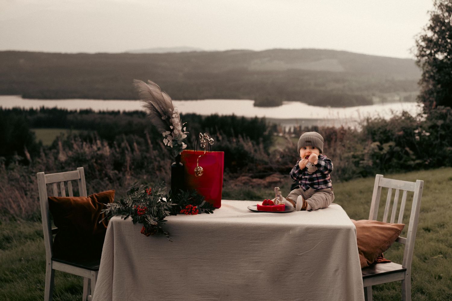 Rustic outdoor table setting with chairs overlooking a scenic mountain landscape.