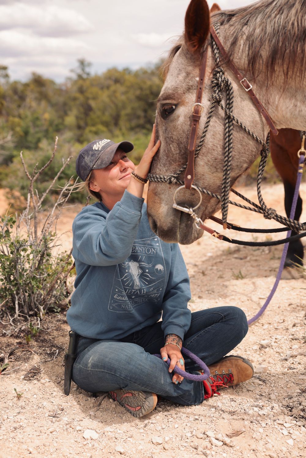 A horse receives gentle affection while standing on a dirt trail in a natural outdoor setting.