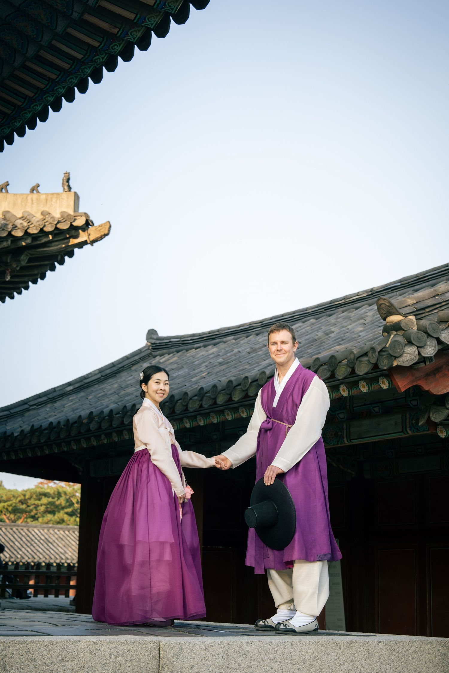 People wearing traditional Korean hanbok clothing pose in sequence against historic temple architecture.