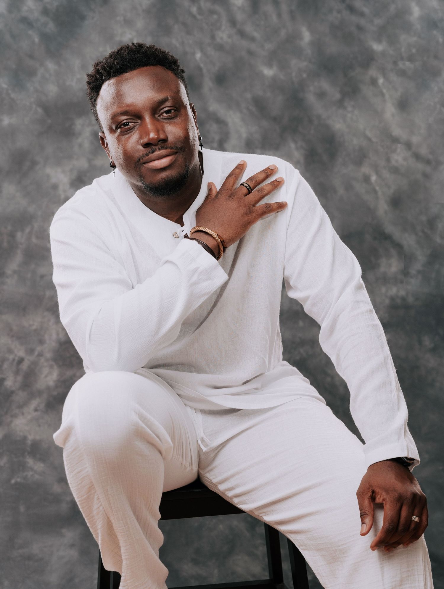 A person in an all-white outfit poses against a gray backdrop in a series of artistic portrait shots.