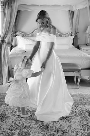 A sequence of black and white photos shows a bride in a flowing white gown interacting with a small child in matching white.