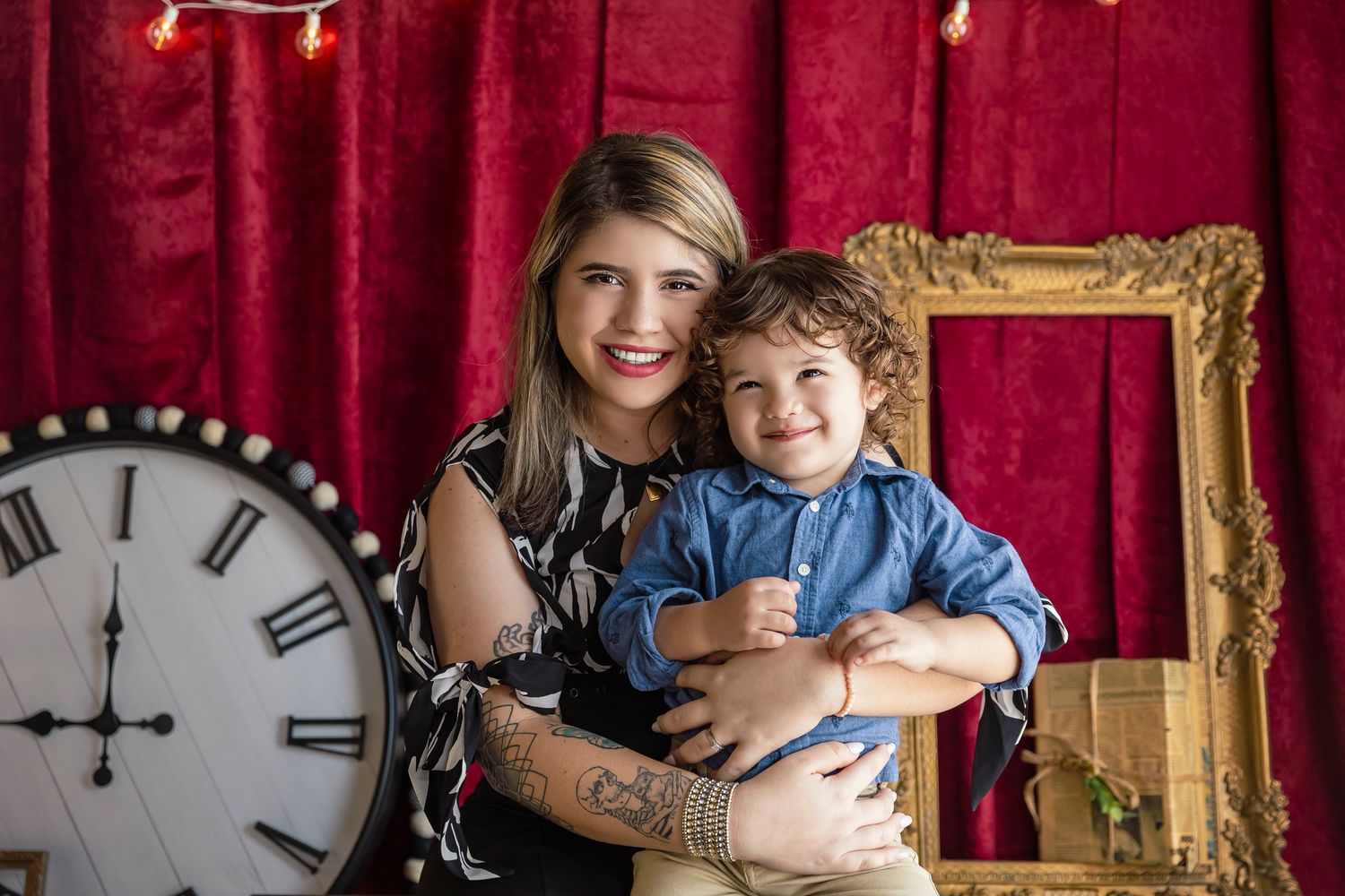 little boy sits on mommy's lap while both smile for a photoshoot
