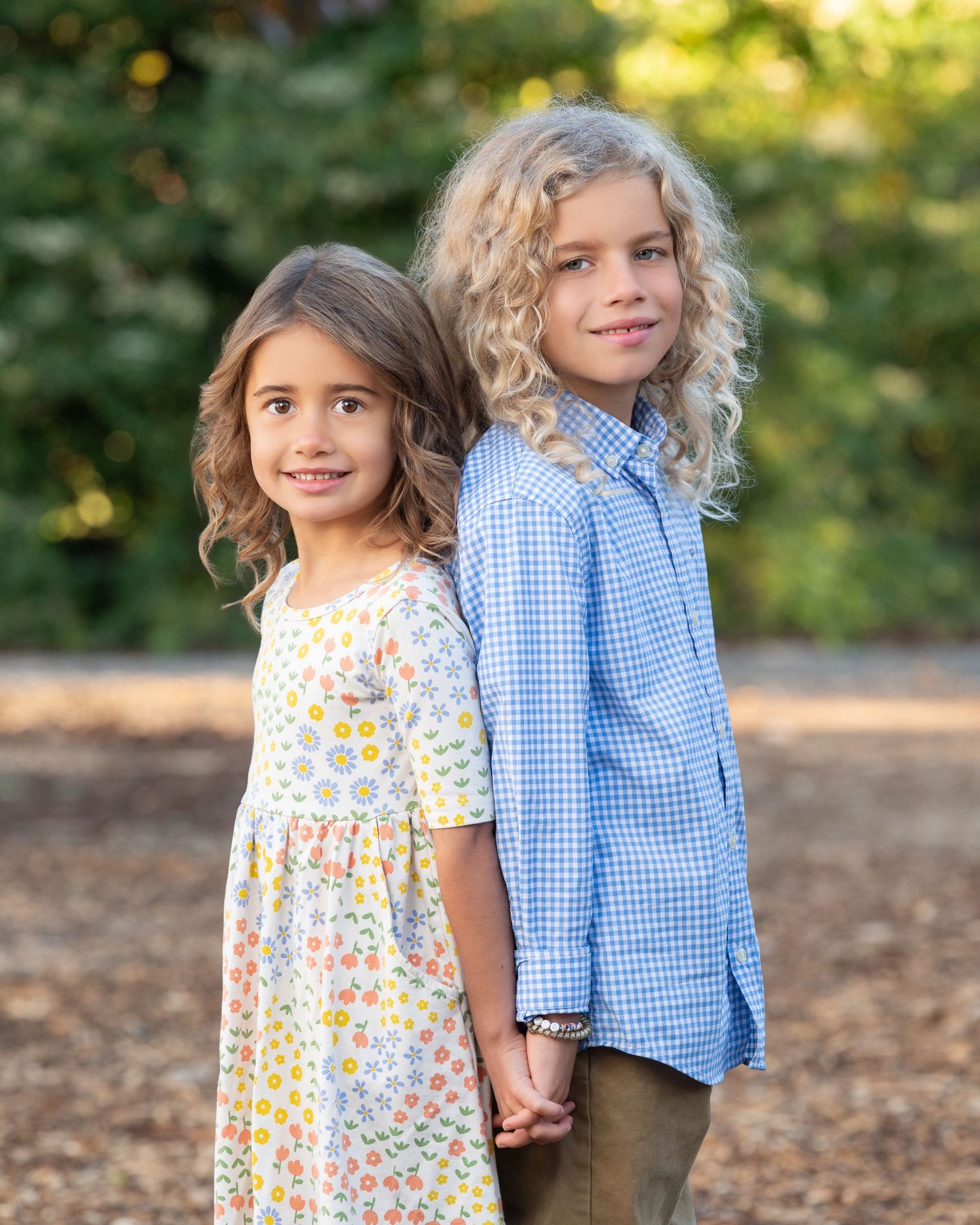 Two children in winter clothing standing together against green outdoor background.