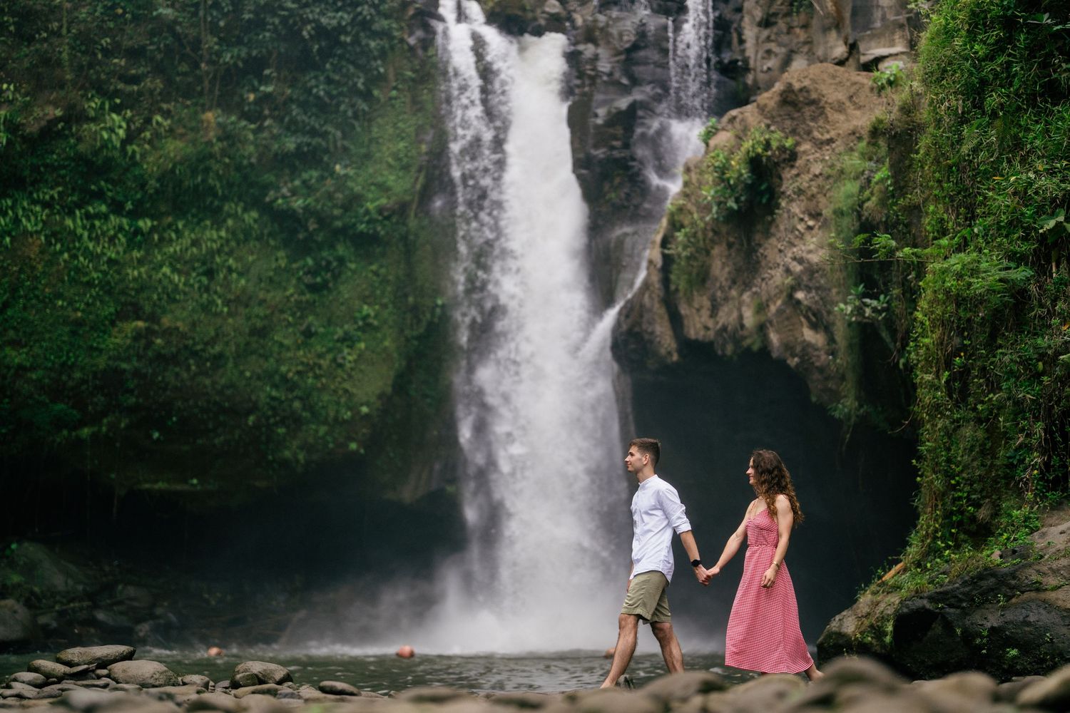 Dramatic waterfall cascades down rocky cliffs surrounded by tropical vegetation.
