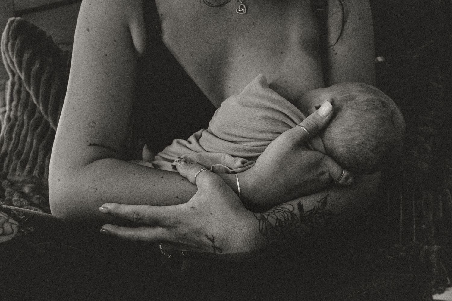 A tender black and white photograph showing a baby being nursed and cradled in loving arms.