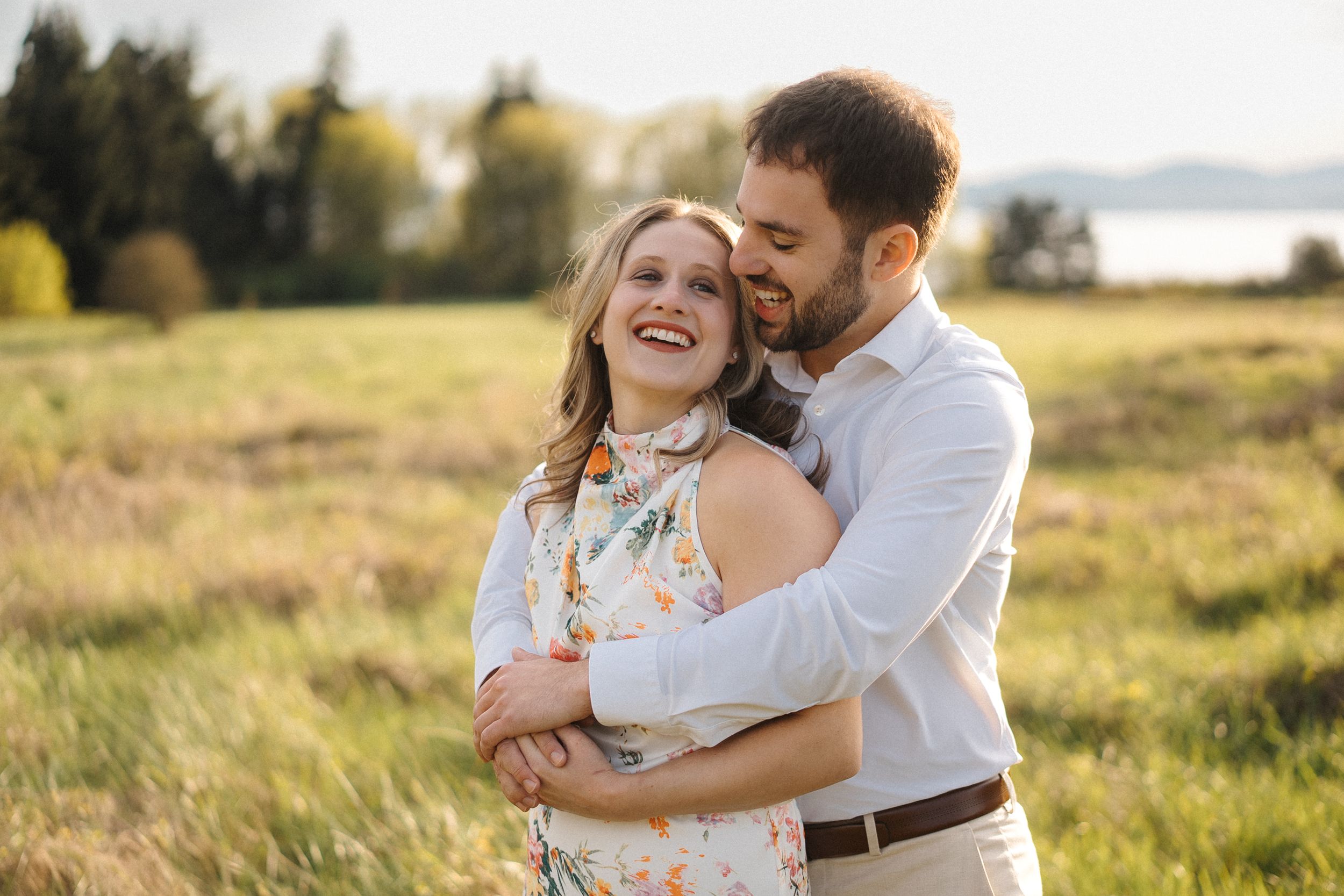 A couple shares a tender moment in a golden sunlit field during sunset.