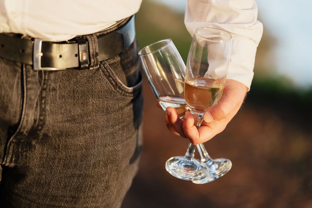 Couple embracing outdoors in casual denim and white attire during golden hour.