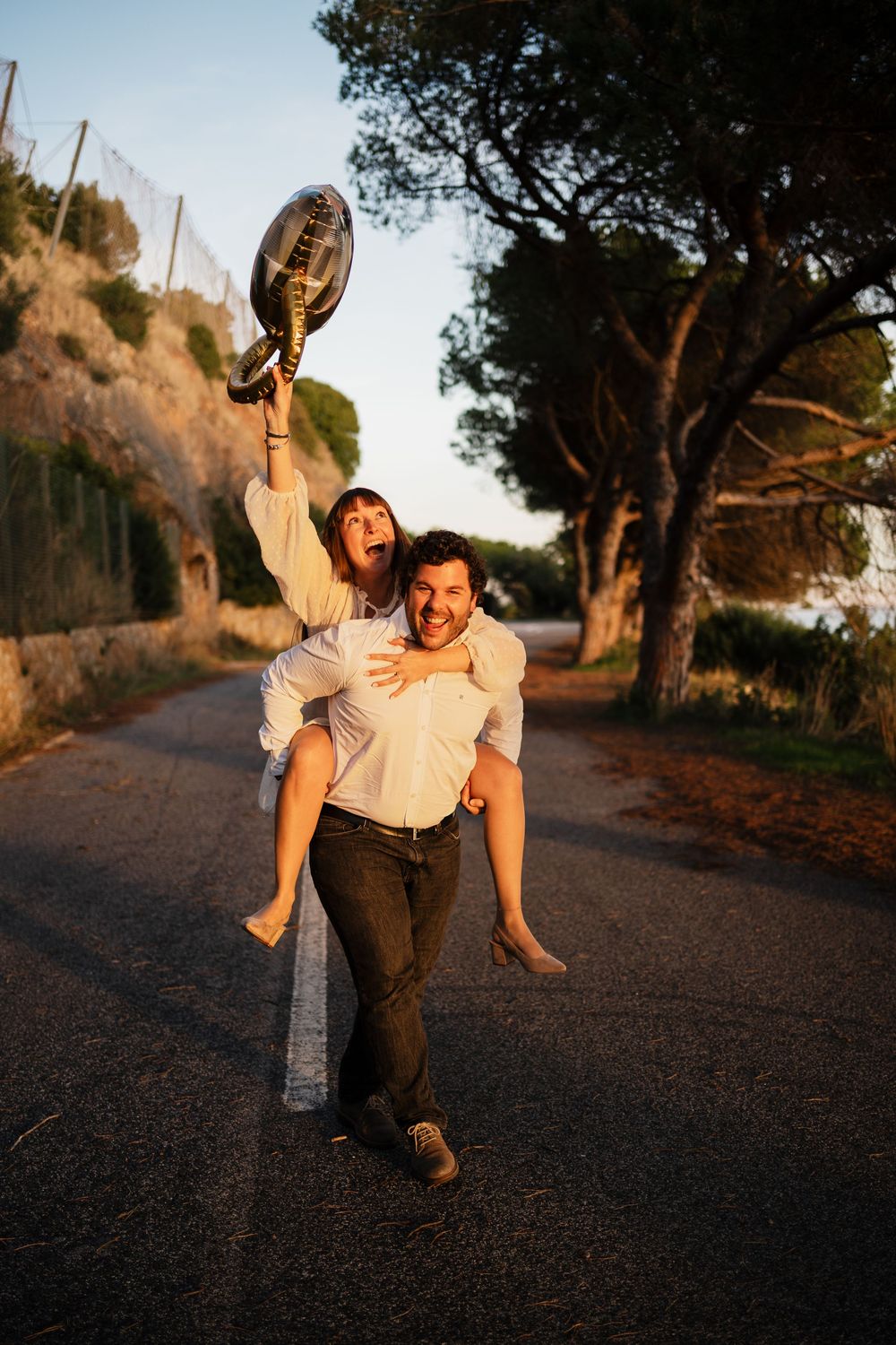 A playful sequence of someone falling down on a dirt path at sunset while wearing casual clothing.