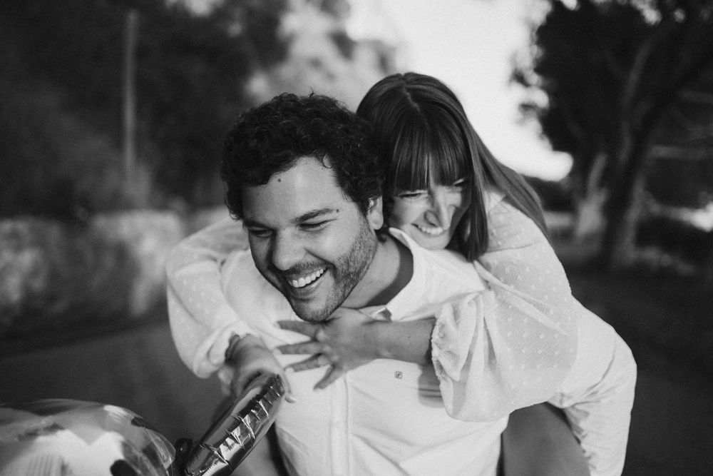 A joyful black and white moment captured outdoors as two people share laughter together.