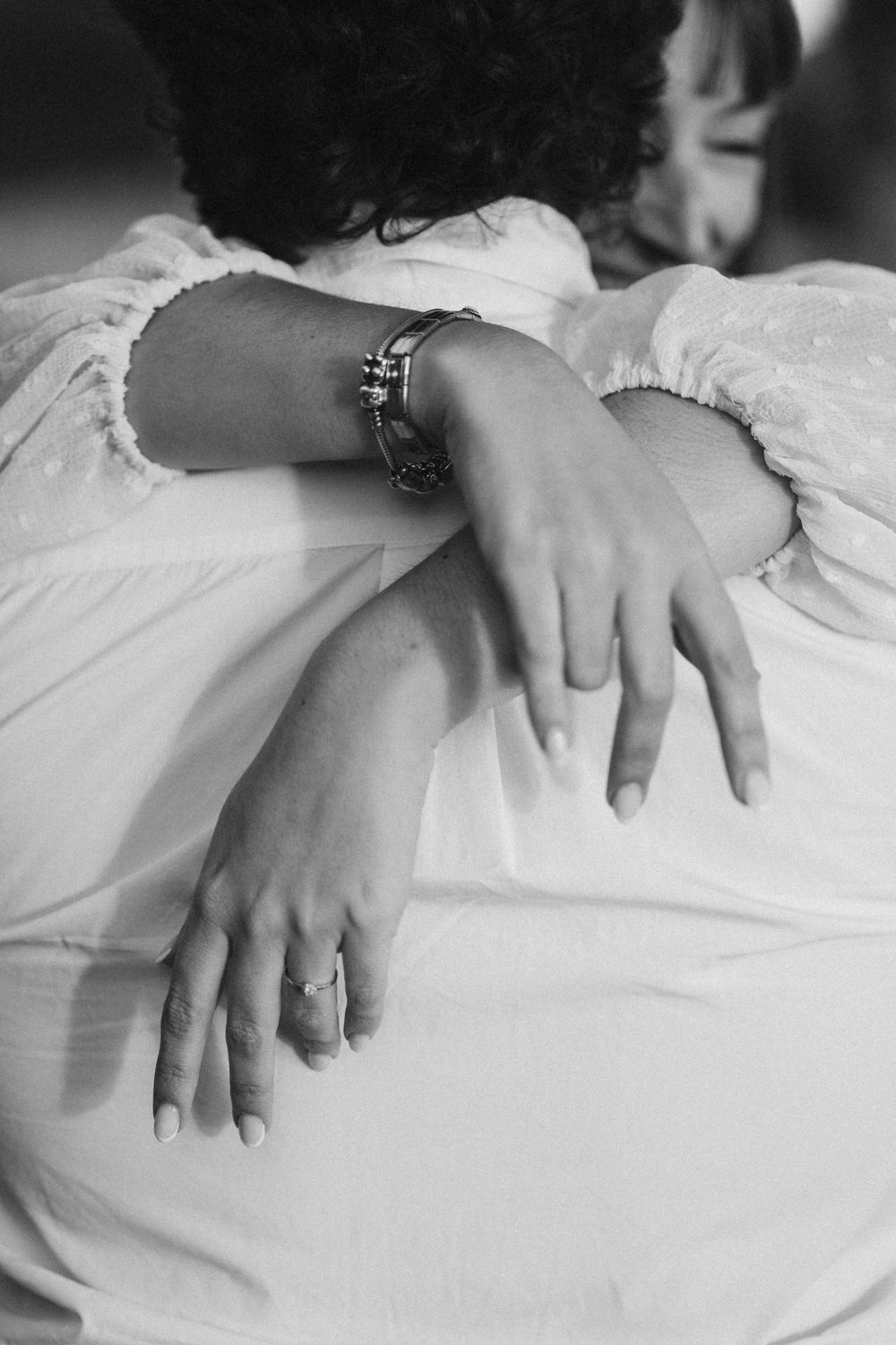 Close-up black and white shots of hands resting on white bedsheets.