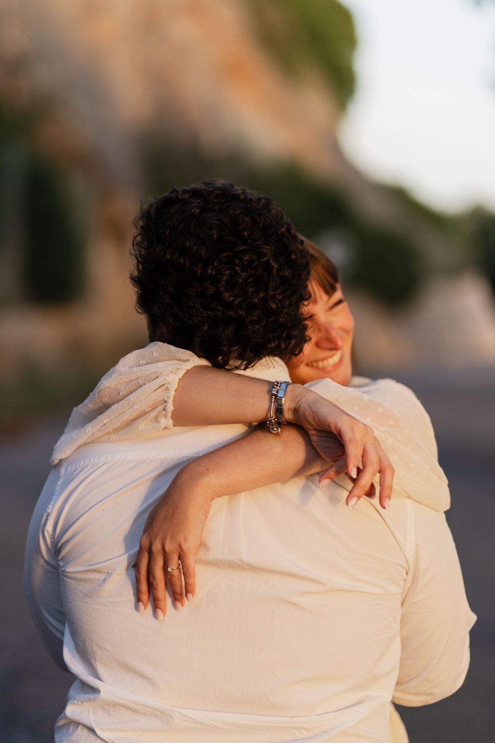 A tender embrace between two people wearing white clothing in warm sunset lighting.