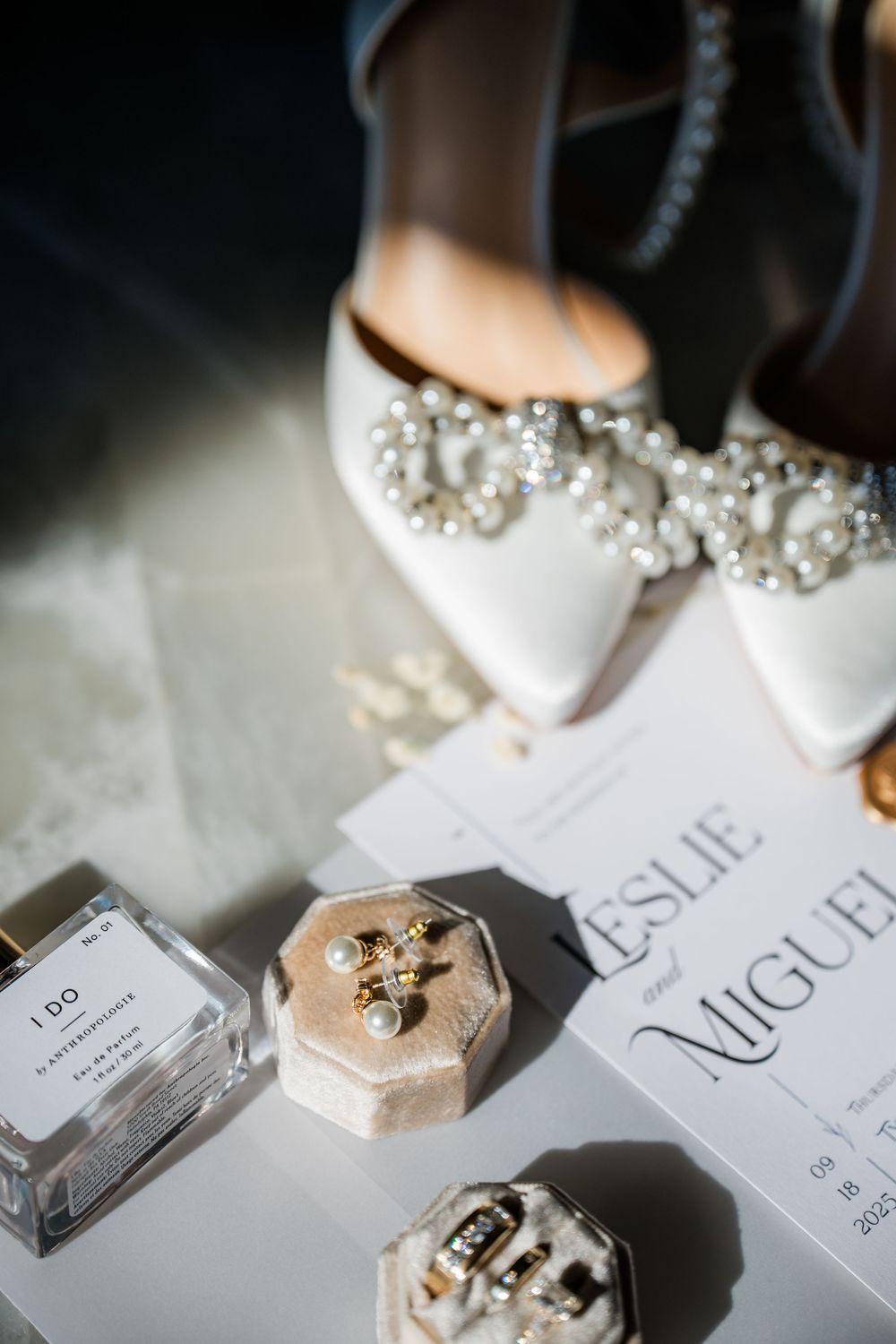Elegant bridal shoes with pearl details displayed alongside wedding stationery.
