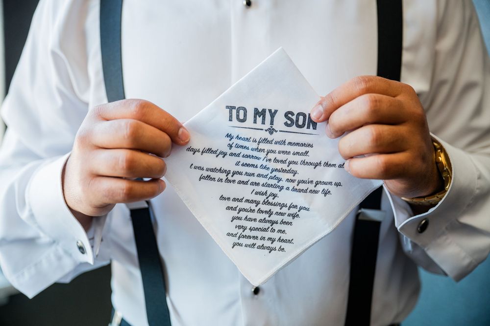 Multiple hands holding up white papers with text that appears to be a poem or letter titled 'To My Son'.