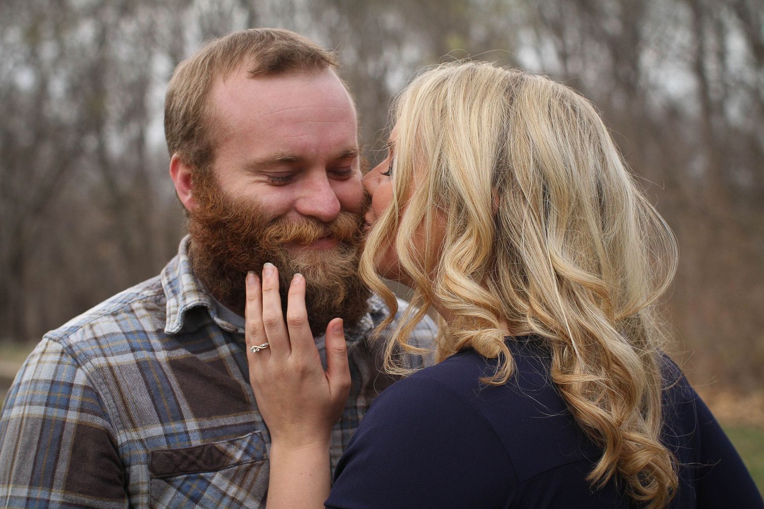 A closeup of a woman kissing her fiance on the cheek during their engagement photo session in Kansas City, Missouri.