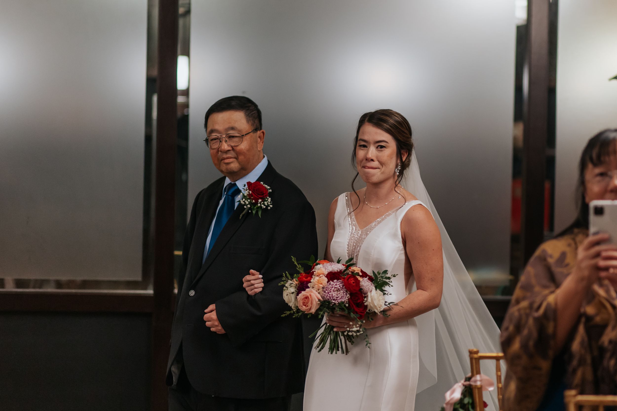 A couple shares their first dance at a wedding reception in a dimly lit venue with guests watching.