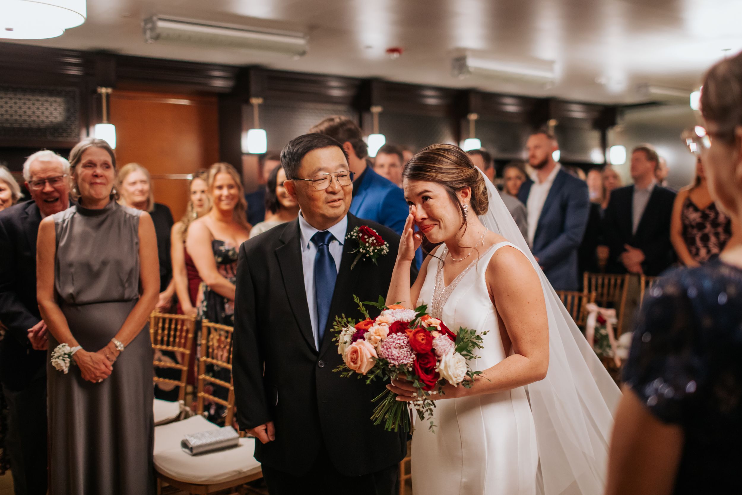 Elegant wedding ceremony in a warmly lit indoor venue with guests seated in rows watching the couple at the altar.