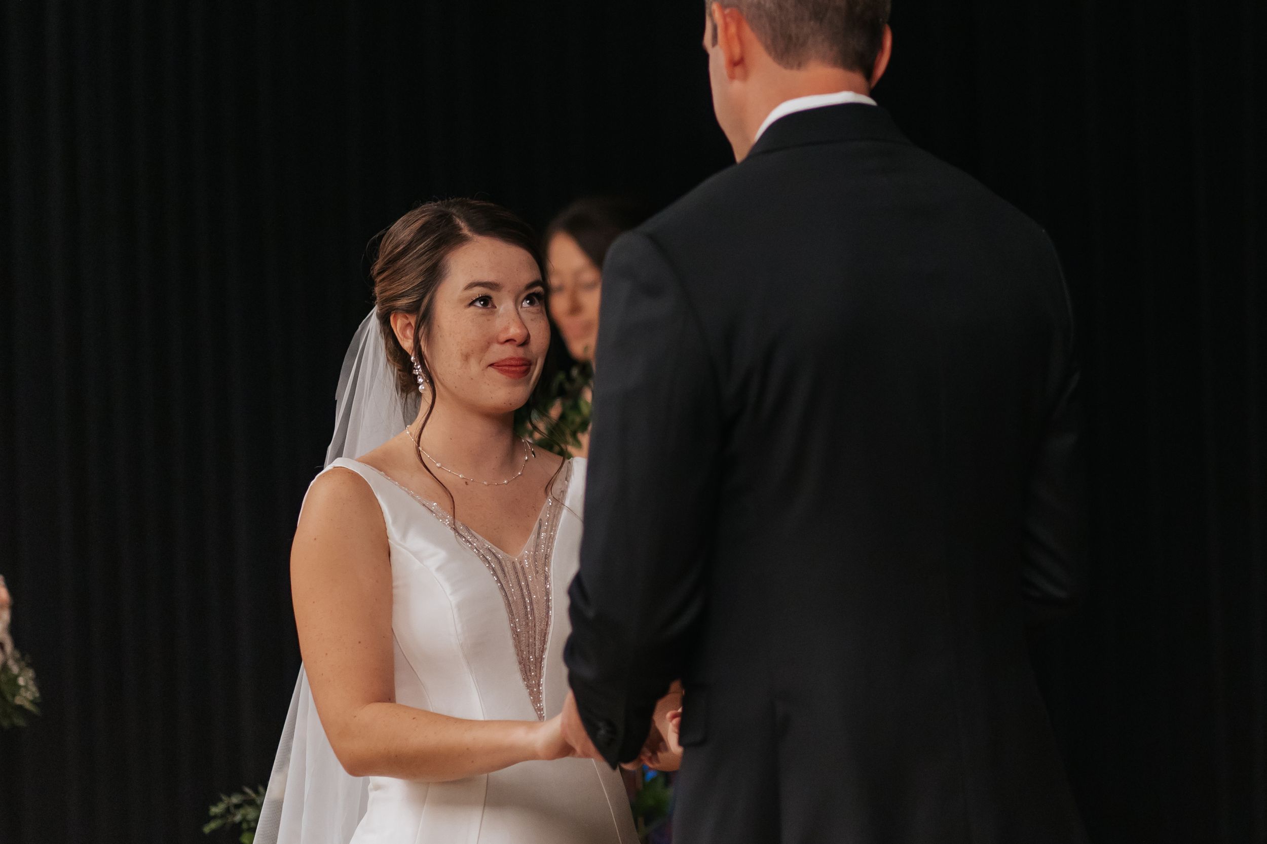 Bride and groom share an intimate moment during their first dance at an indoor wedding reception.