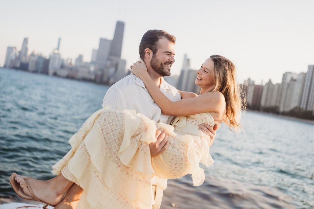 A joyful couple dances and laughs together by the waterfront with the Chicago skyline in the background.
