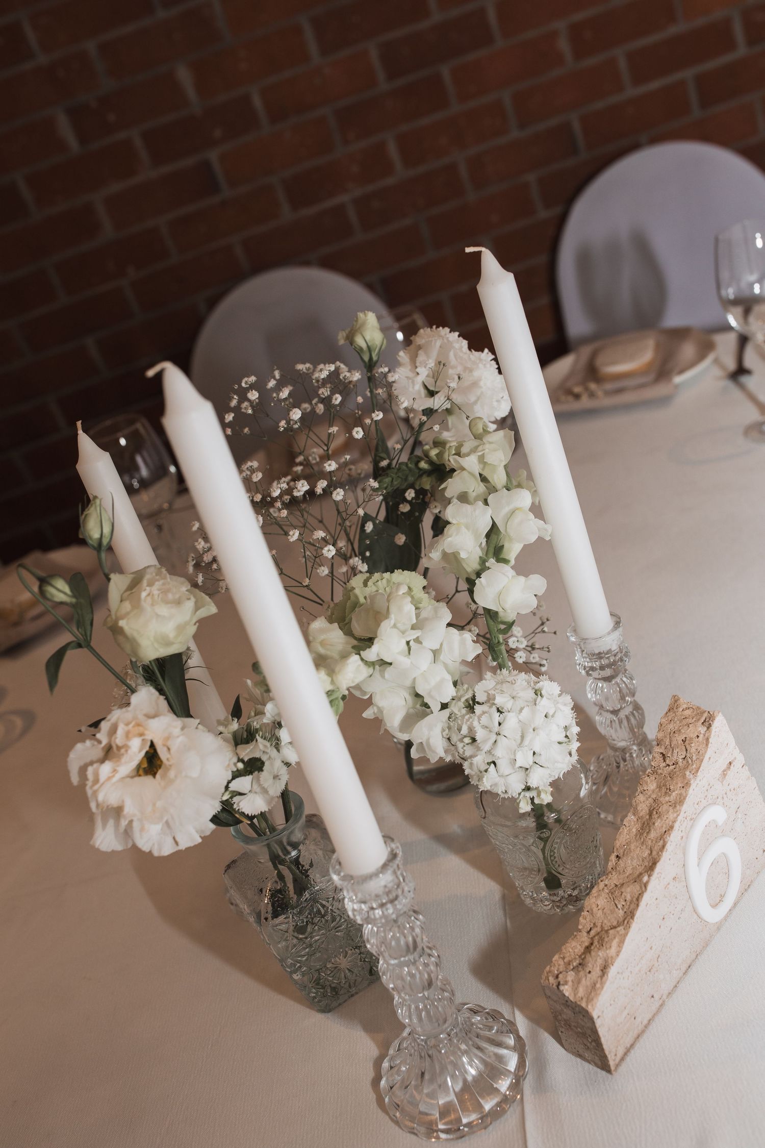 White taper candles and delicate floral arrangements in crystal vases create an elegant table centerpiece display.