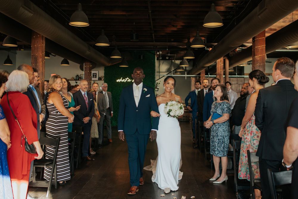 Wedding guests mingle and socialize during a reception in a dimly lit indoor venue.