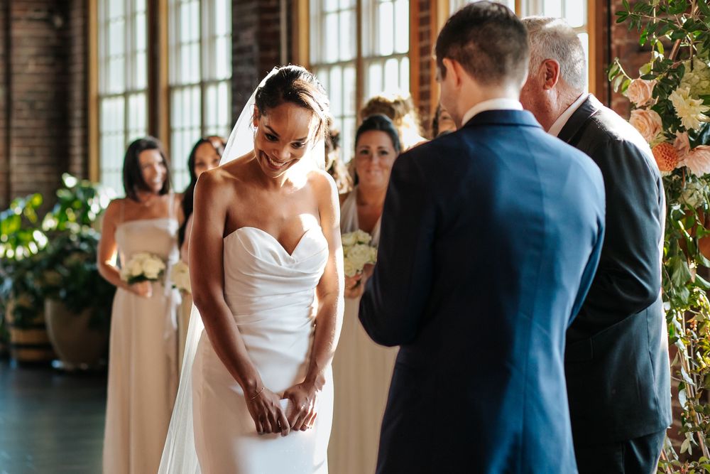 Wedding ceremony in a rustic industrial venue with exposed brick walls and large windows.