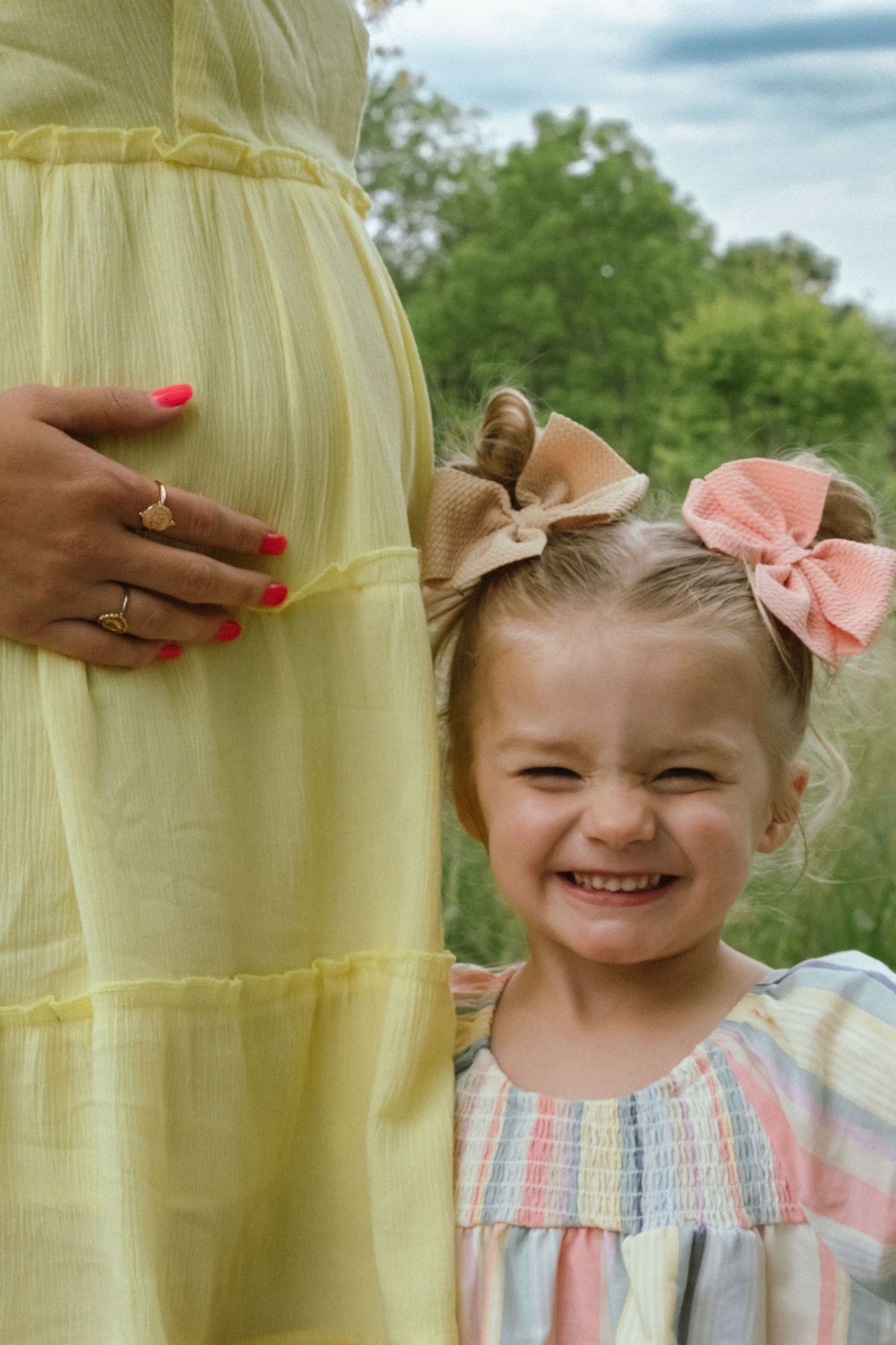 a little girl standing in front of her mother's belly, excited to become a big sister