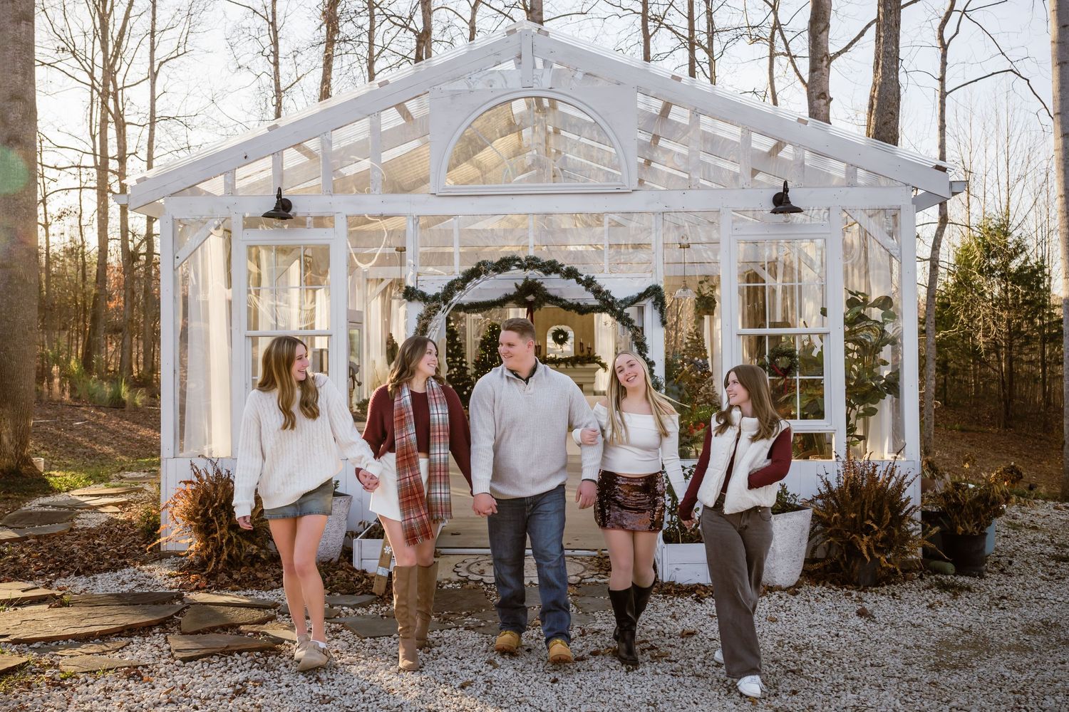 A group gathers under a clear tent structure in a wooded outdoor setting during a special event celebration.