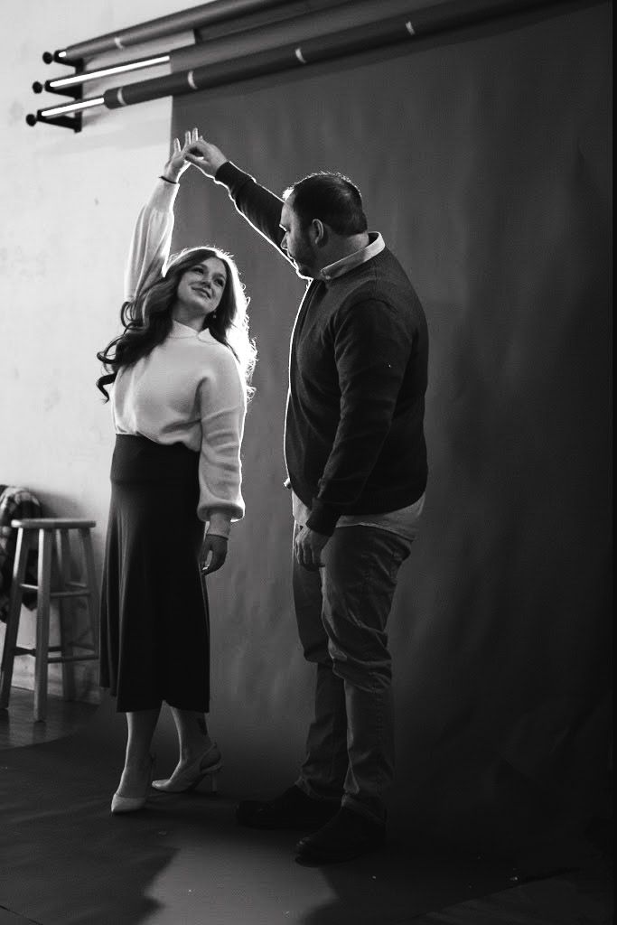 A couple dancing together in a romantic black and white photo against a dark background.