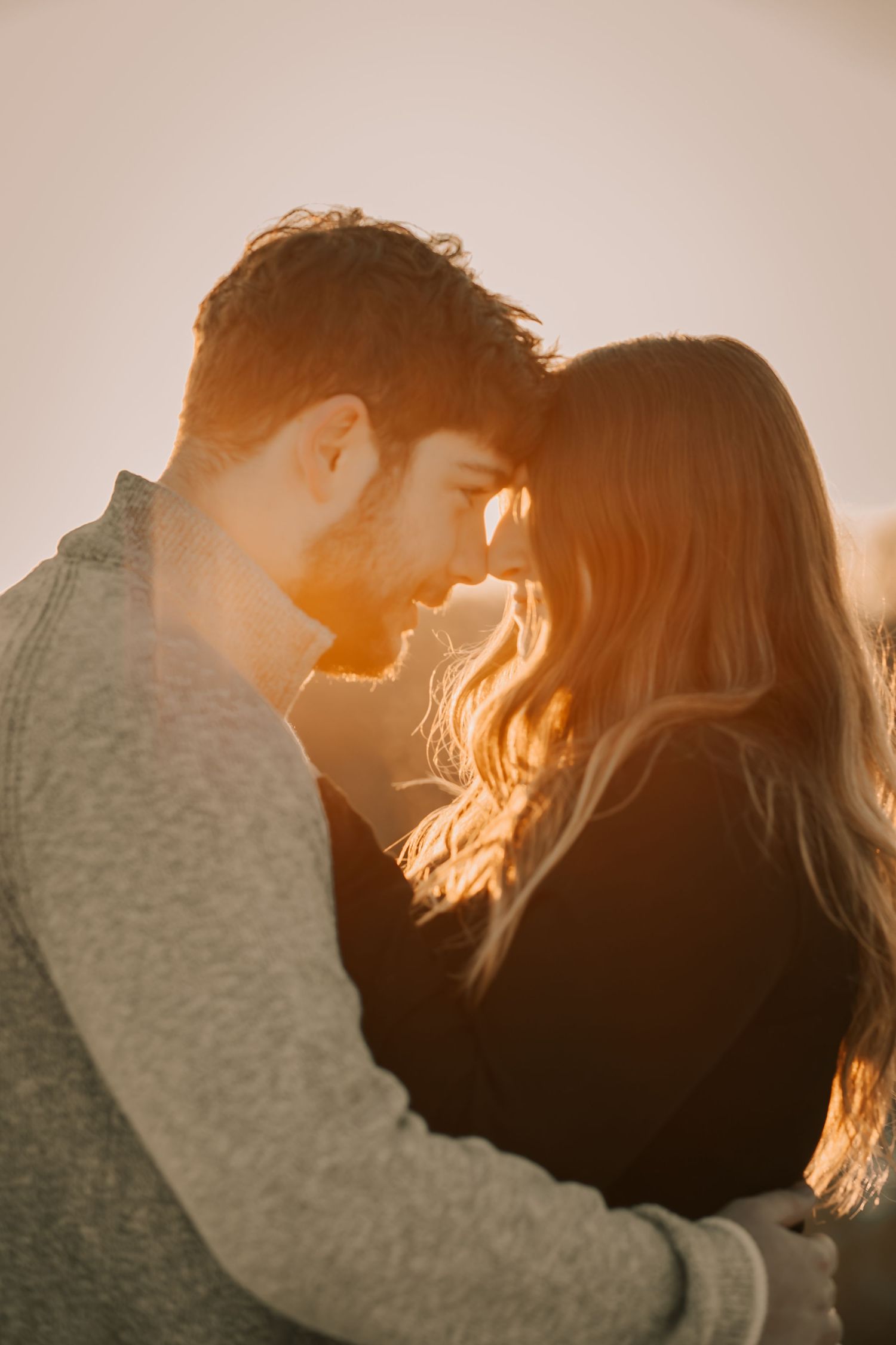Silhouetted couple embracing in golden sunlight creating romantic backlit portraits at sunset.