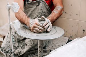 Mani che lavorano l'argilla su un tornio da vasaio, modellando e plasmando il materiale in un processo creativo.