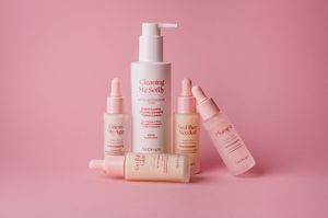 Prodotti di bellezza e per la cura della pelle disposti artisticamente su uno sfondo rosa che mostra vari flaconi e contenitori.