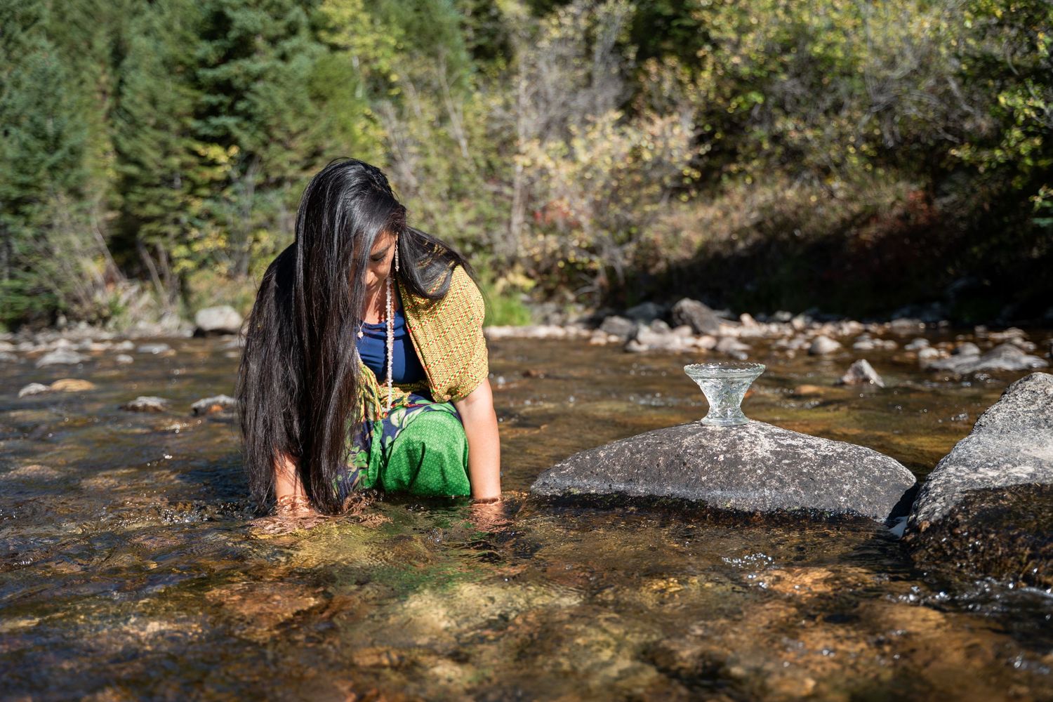 People enjoying a summer day cooling off in a rocky mountain stream with crystal clear water.