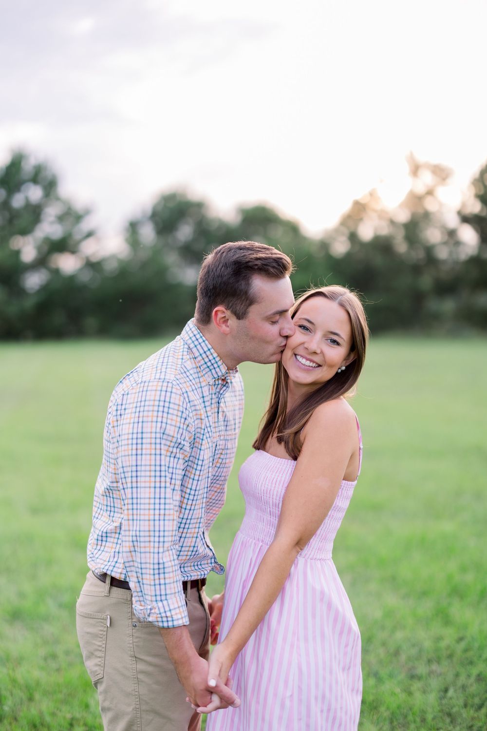 A romantic moment captured between two people in a sunlit meadow.