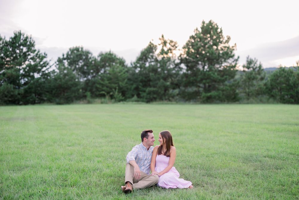 A couple sits together on grass during a romantic outdoor photoshoot.