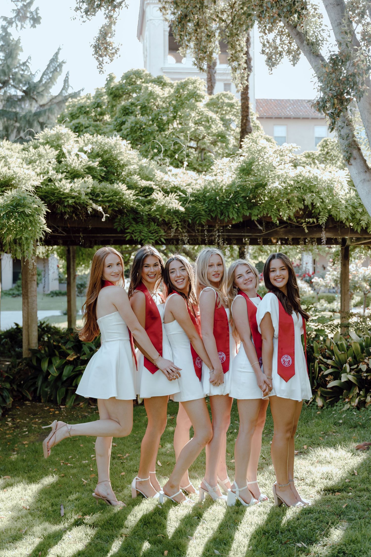Santa Clara University group of college graduates take photos together with a backdrop of greenery. by Bay Area Graduation Photographer.